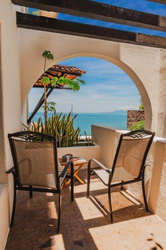 two chairs and an umbrella on a patio with the ocean at Luxury Oceanview Condo with heated Pool in Puerto Vallarta
