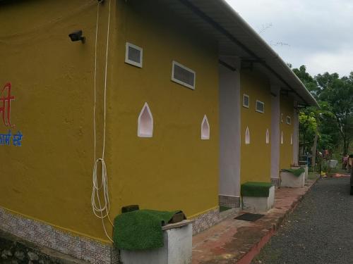 a yellow building with white windows on the side of it at Tarangini Farmstay in Maheshwar