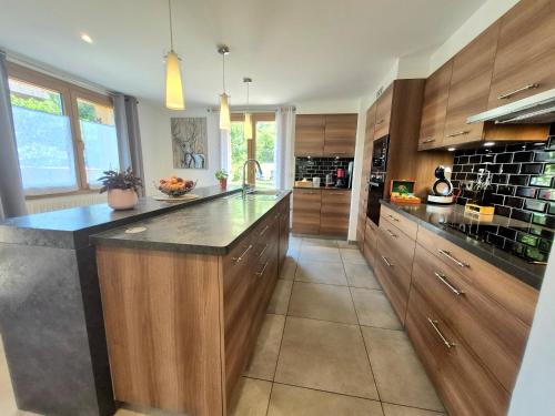 a large kitchen with wooden cabinets and a large island at Chalet avec Jacuzzi, billard, jardin clos, proche Paradiski in Aime La Plagne