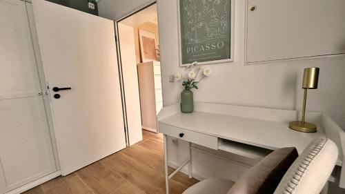 Un escritorio blanco con un jarrón de flores en una habitación. en Sonnenplatz mit Parkplatz - Zentral und Elegant, en Bad Rothenfelde