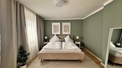 Un dormitorio con una cama con paredes verdes y un espejo. en Sonnenplatz mit Parkplatz - Zentral und Elegant, en Bad Rothenfelde