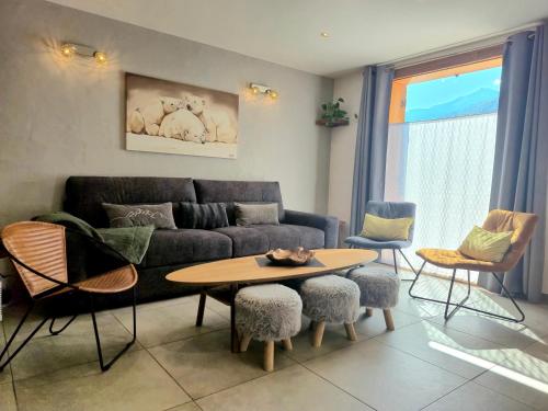 a living room with a couch and a table and chairs at Chalet avec Jacuzzi, billard, jardin clos, proche Paradiski in Aime La Plagne
