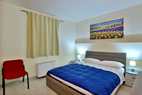 a bedroom with a bed and a red chair at Ca' Rossa in Roe