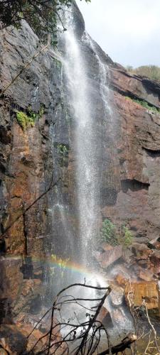 a waterfall with a rainbow on the side of a cliff at Heeloya mount view garden in Kurukohogama