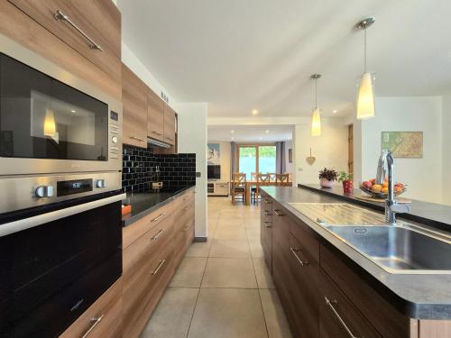a large kitchen with a sink and a microwave at Chalet avec Jacuzzi, billard, jardin clos, proche Paradiski in Aime La Plagne