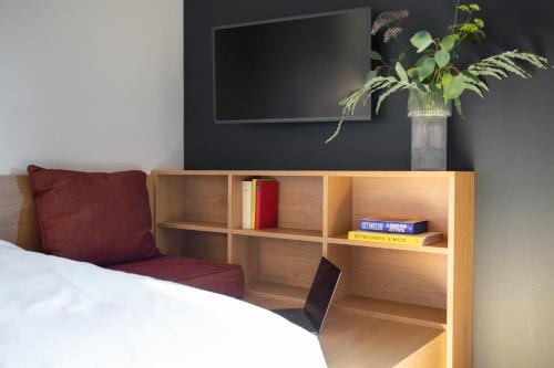 a book shelf with a television and a vase with a plant at STAYERY Bielefeld Hauptbahnhof in Bielefeld
