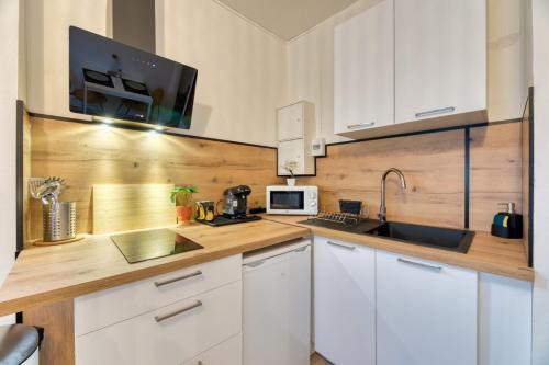 a kitchen with white cabinets and a sink and a microwave at Ceylan bel F2 à Rouen in Rouen