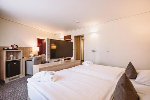 a hotel room with two beds and a flat screen tv at Hotel Gustav-Stresemann-Institut in Bonn