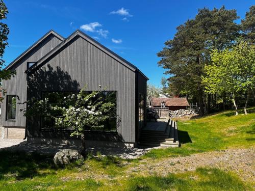 a black building with a tree in front of it at Large villa Tjärnö Strömstad in Strömstad