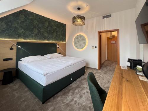 a bedroom with a large bed with a green headboard at Hotel Slovan in Jeseník