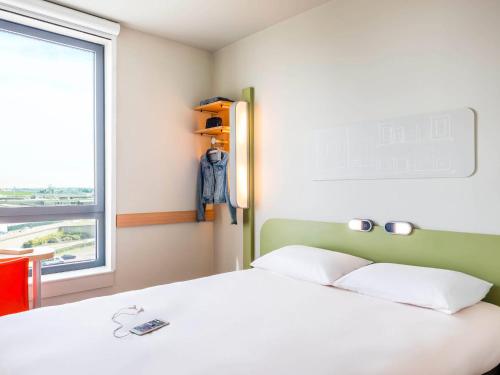 a bedroom with a white bed and a window at ibis budget Paris Coeur d'Orly Airport in Orly