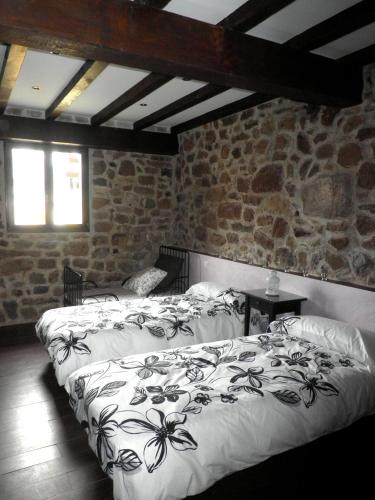 a bedroom with two beds and a stone wall at Casa Rural La Charruca in Abionzo