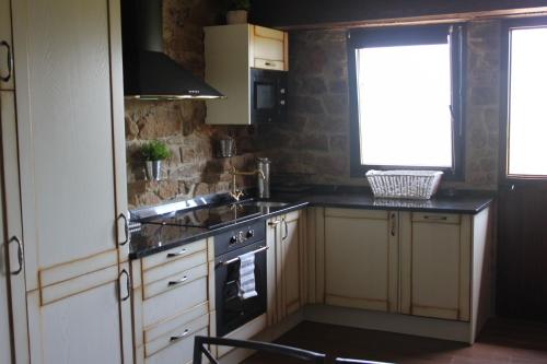 cocina con fogones, fregadero y ventana en Casa Rural La Charruca, en Abionzo