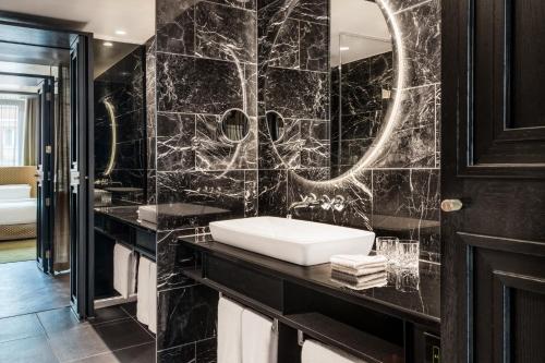 a black bathroom with a sink and a mirror at Roomers Munich, Autograph Collection in Munich