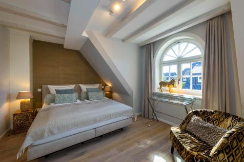 a bedroom with a bed and a chair and a window at Haus Sylter Schönheit in Westerland