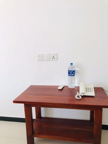 a wooden table with a telephone and a bottle of water at Sunstar Nilaveli in Trincomalee