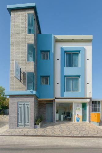 a blue building with a woman in the window at Hotel Vista Caribe Azúa in Azua de Compostela