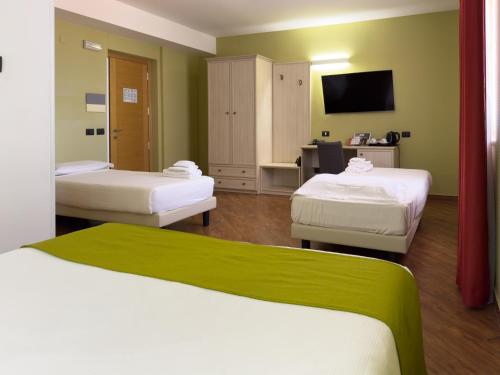a hotel room with two beds and a flat screen tv at Simon Hotel in Pomezia