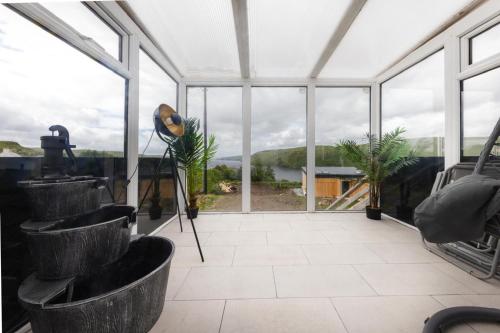 a greenhouse with large windows and a view of the water at Luxury Seaview Cottage by Fairy Pools 3 in Carbost