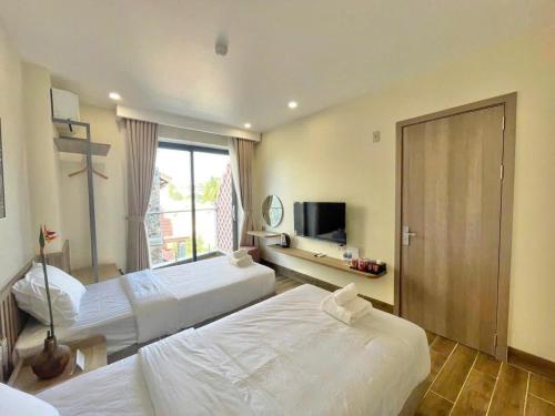 a hotel room with two beds and a television at Cham Charm Home Mui Ne in Mui Ne