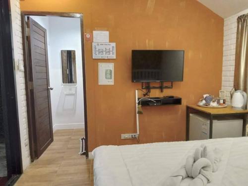 Zimmer mit einem Bett und einem TV an der Wand in der Unterkunft V Village Hotel Saraburi in Ban Muak Lek