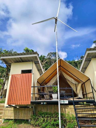 a house with a wind turbine on the front of it at Bansuanariya in Ban Na Yang