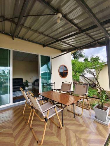 a wooden table and chairs on a patio at Bansuanariya in Ban Na Yang