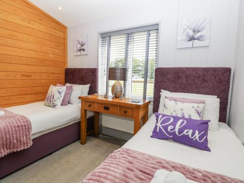 a bedroom with two beds and a night stand at Angel Lodge - No 27 in Hengrave