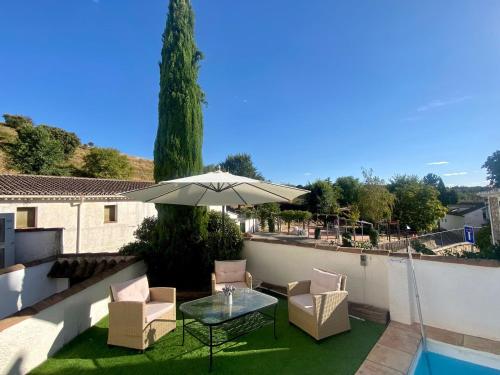 eine Terrasse mit Tisch und Stühlen und einem Sonnenschirm in der Unterkunft La Senda de Olmeda in Olmeda de las Fuentes