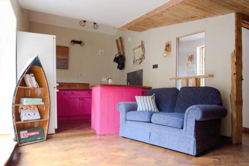 a living room with a blue couch and pink cabinets at Conkers 
