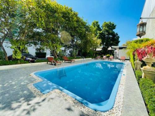 a blue swimming pool in a yard with trees at Harmonize Hotel Chiang Mai in Chiang Mai