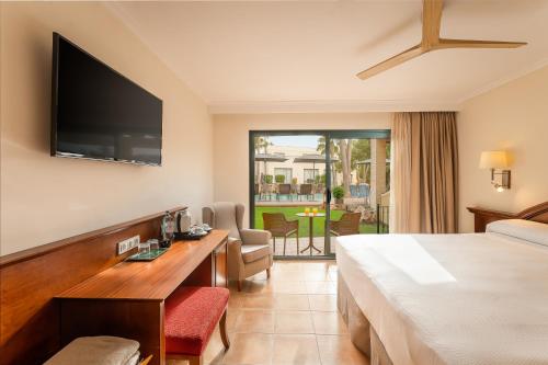 a hotel room with a bed and a desk and a television at Valentin Star Menorca - Adults Only in Cala'n Bosch