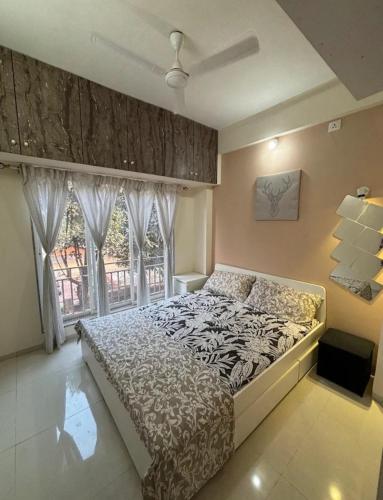 a bedroom with a bed and a large window at CASA HILLSIDE Dapoli 2BHK AC Apartment in Dapoli