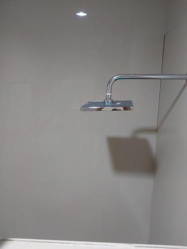 a shower with a silver shower head on a wall at Buratwangi Tropis House in Kerobokan