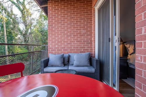 a patio with a red table and chairs on a balcony at Classic City Getaway - Walk to Sanford Stadium in Athens