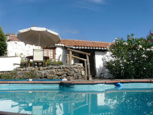una piscina con sombrilla y una casa en Casa Pepa en Granadilla de Abona