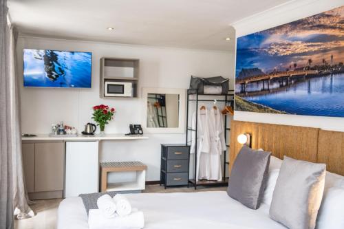 a bedroom with a white bed and a kitchen at Cape Diamond Boutique Hotel in Cape Town