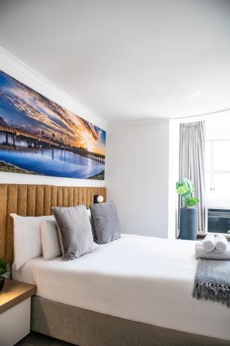 a bedroom with a large bed with a painting on the wall at Cape Diamond Boutique Hotel in Cape Town