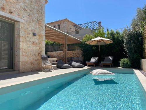 a swimming pool with an umbrella next to a house at PAPADRIA VILLAS - Modern Luxury villas near Kathisma Beach in Tsoukaladhes
