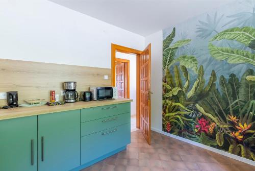 Una cocina con gabinetes azules y un mural. en Chez Mamie Wifi Un Séjour à Part, en Moyeuvre-Grande