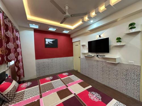 a room with a red wall and a flat screen tv at Pablo Place in Ghaziabad