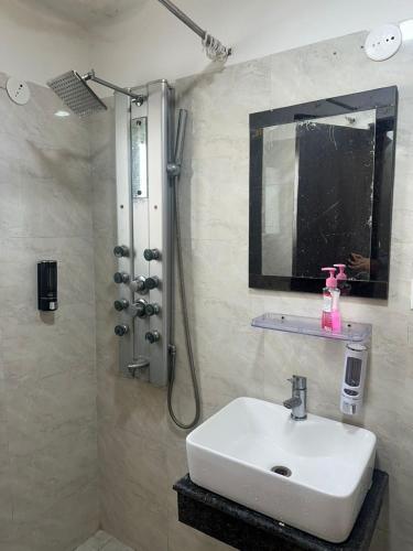 a bathroom with a sink and a shower with a mirror at Pablo Place in Ghaziabad