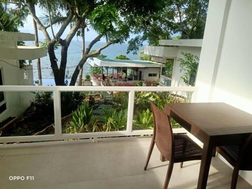 a balcony with a table and chairs and a large window at Tulang Diot View Resort and Turtle Haven in Camotes Islands