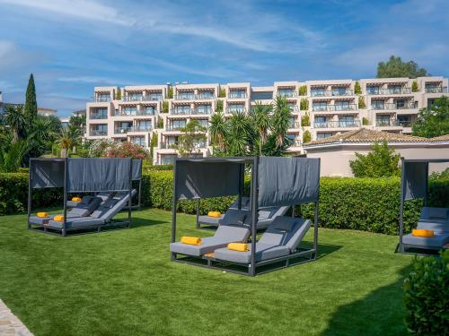a row of lounge chairs on a lawn in front of a building at Dreams Corfu Resort & Spa - All Inclusive in Gouvia