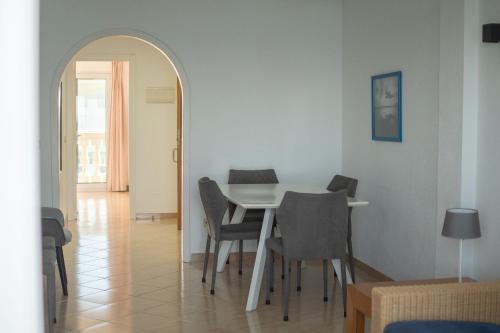 Un comedor con una mesa y sillas blancas. en Apartamentos Dominique, en La Manga del Mar Menor