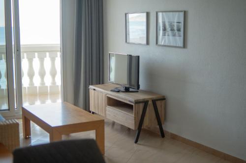 Una sala de estar con un televisor sobre una mesa de madera. en Apartamentos Dominique, en La Manga del Mar Menor