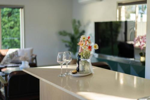 two wine glasses and a vase of flowers on a table at Family Friendly Funhouse close to All Theme Parks in Gold Coast