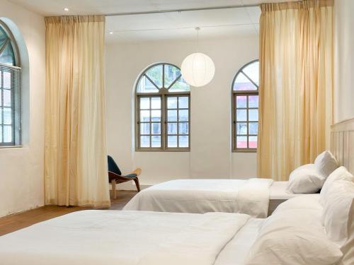 two beds in a room with two windows at Heritage Vacation Inn at Jalan Padungan in Kuching