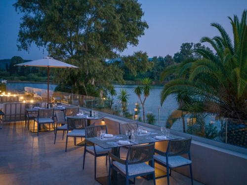 a restaurant with tables and chairs next to a body of water at Dreams Corfu Resort & Spa - All Inclusive in Gouvia