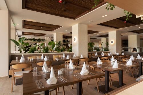 a restaurant with wooden tables and chairs with white napkins on them at Dreams Corfu Resort & Spa - All Inclusive in Gouvia